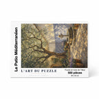 Boîte de puzzle en bois de 500 pièces - Le Patio Méditerranéen, Collection Signature. Le packaging blanc épuré présente une illustration d'un patio ensoleillé avec olivier et azulejos. Fabriqué en bois de tilleul de 2 mm, offrant un assemblage sensoriel et une finition élégante pour la décoration.